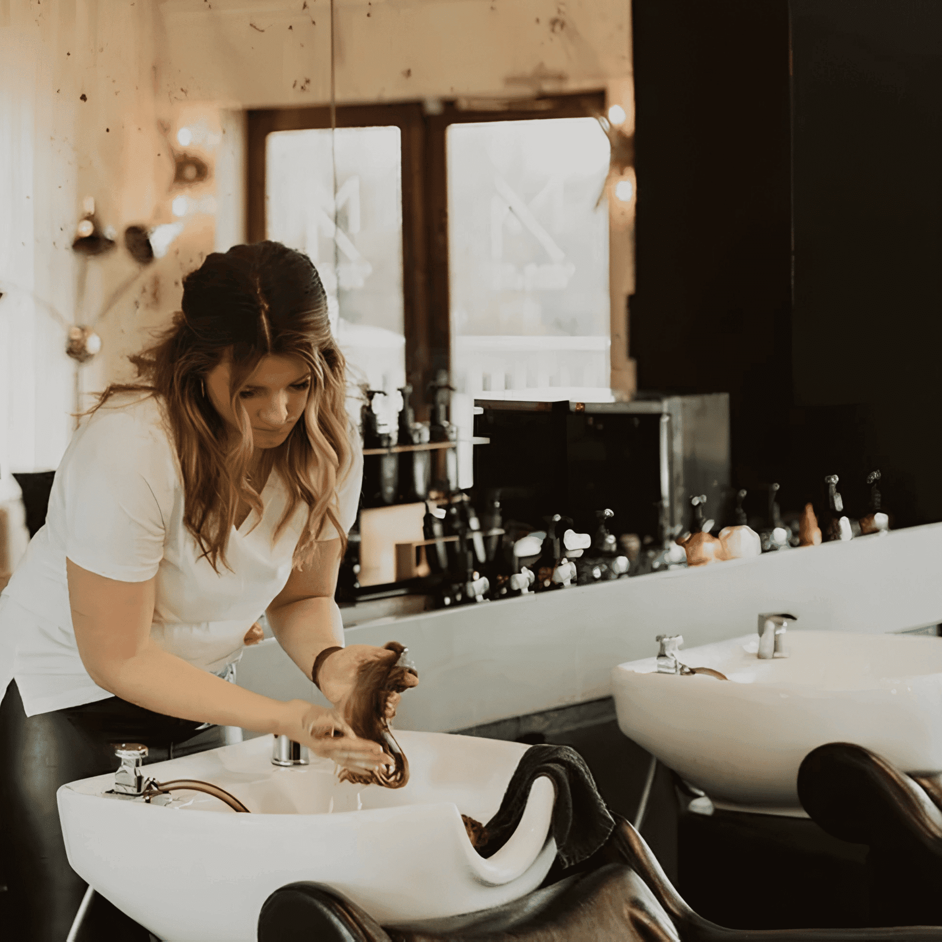 Hairdresser washing client's hair in a modern salon.