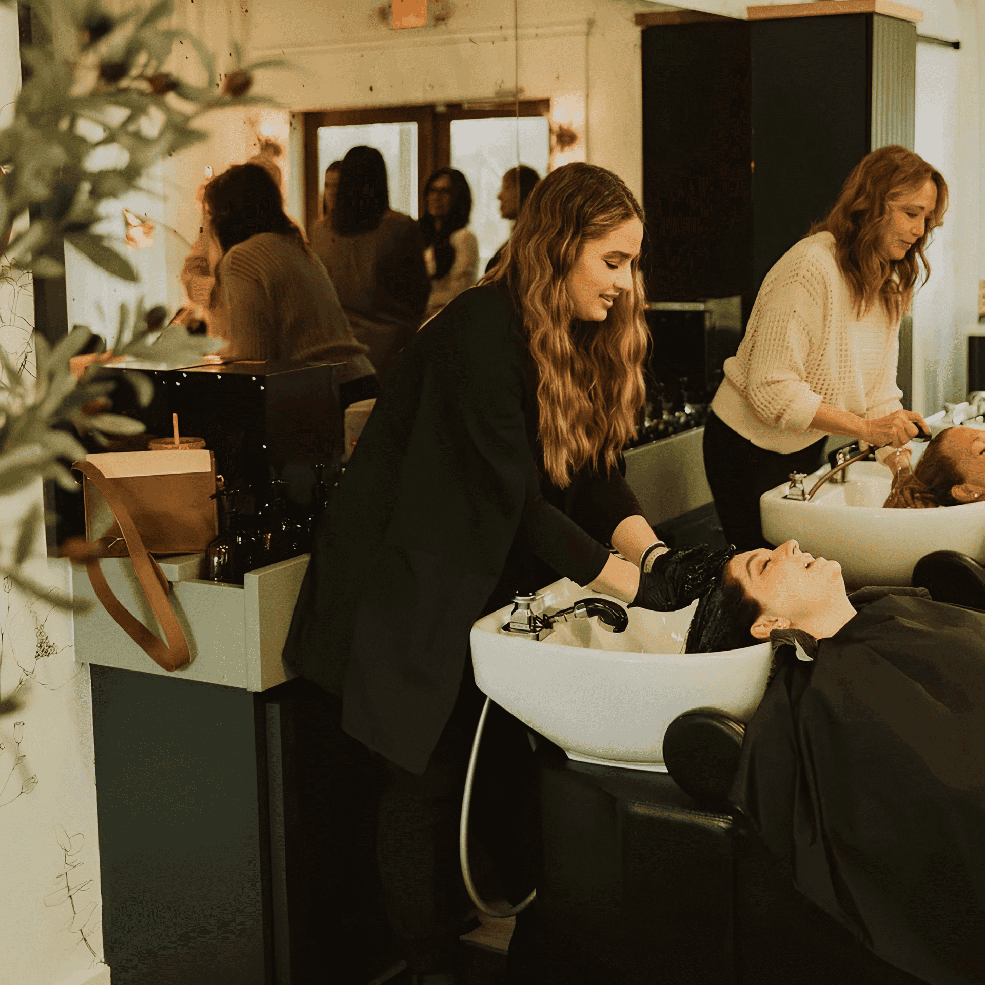 Hair salon interior with stylists washing clients' hair at sinks, creating a relaxing atmosphere.